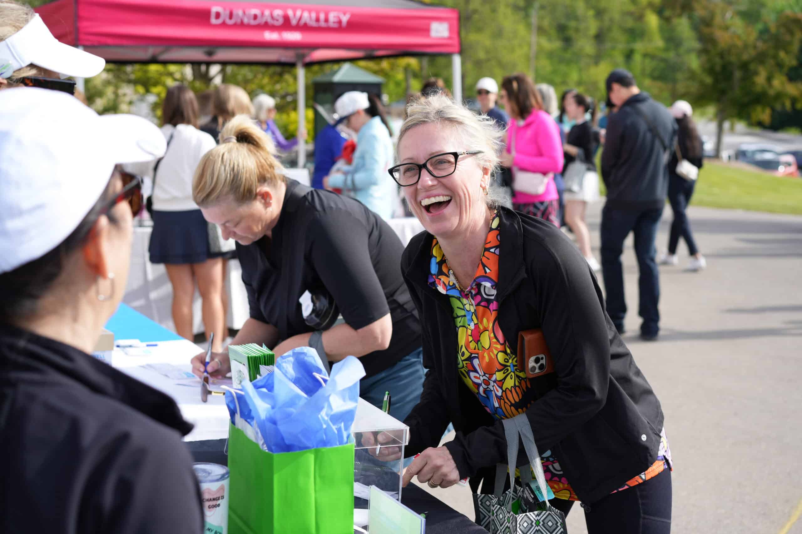 Women laughing at a vendor booth during Smashing Nines registration