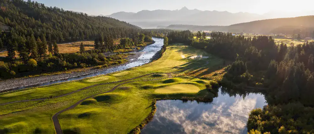 Aerial view of a golf course along a river with mountains in British Columbia
