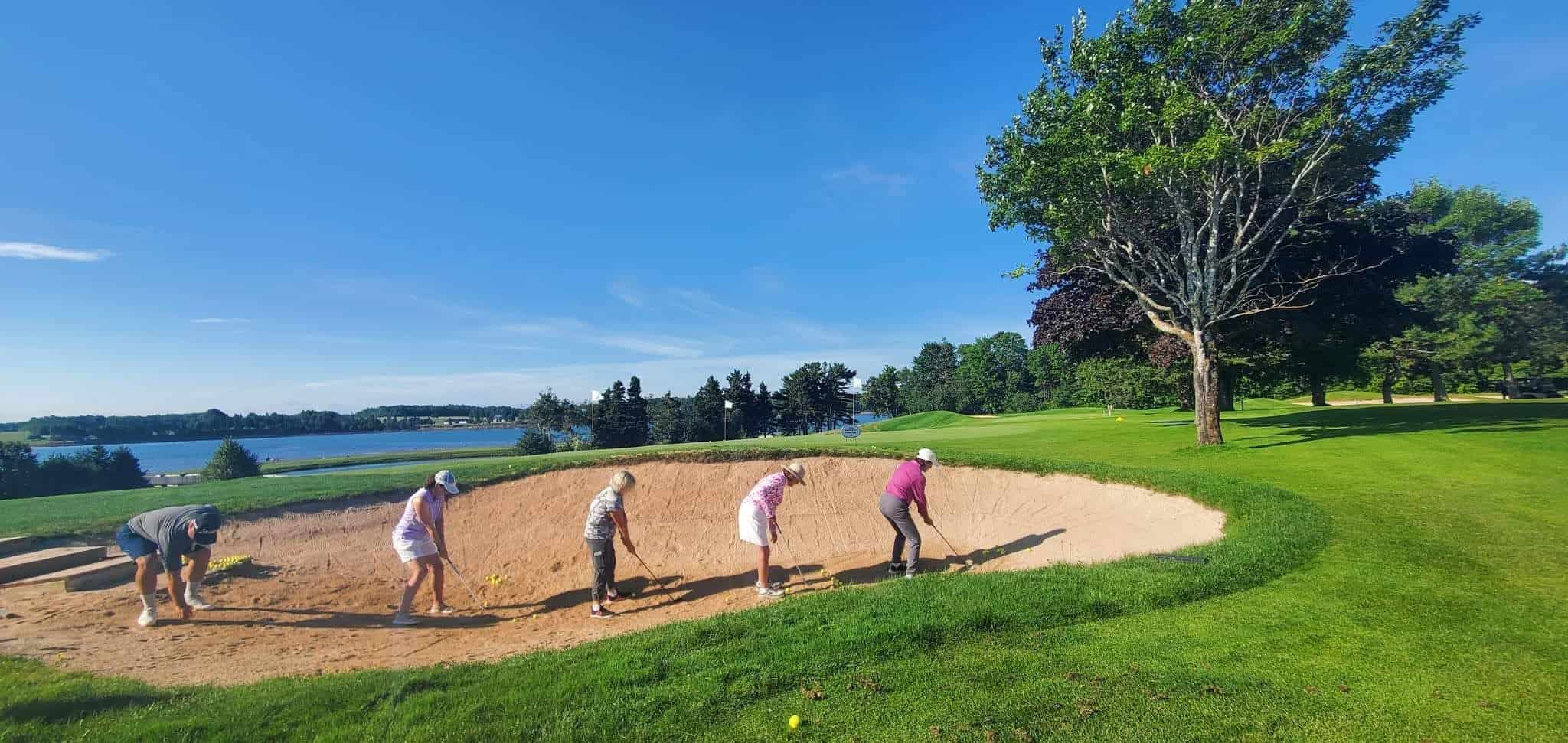 Women practising bunker shots at a golf school in PEI